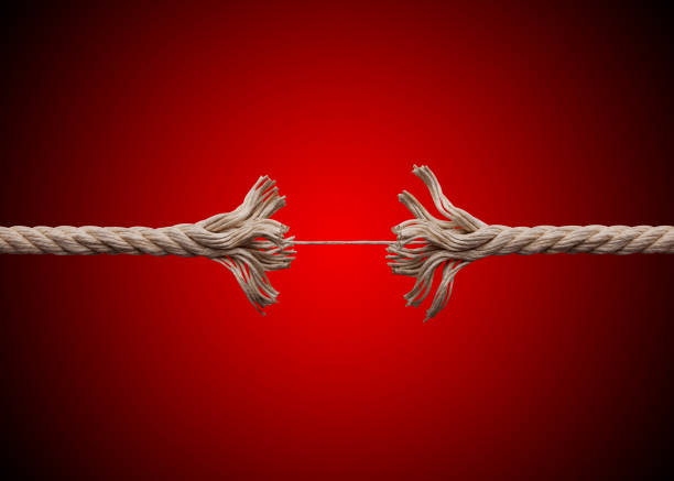 Frayed rope about to break on red background.